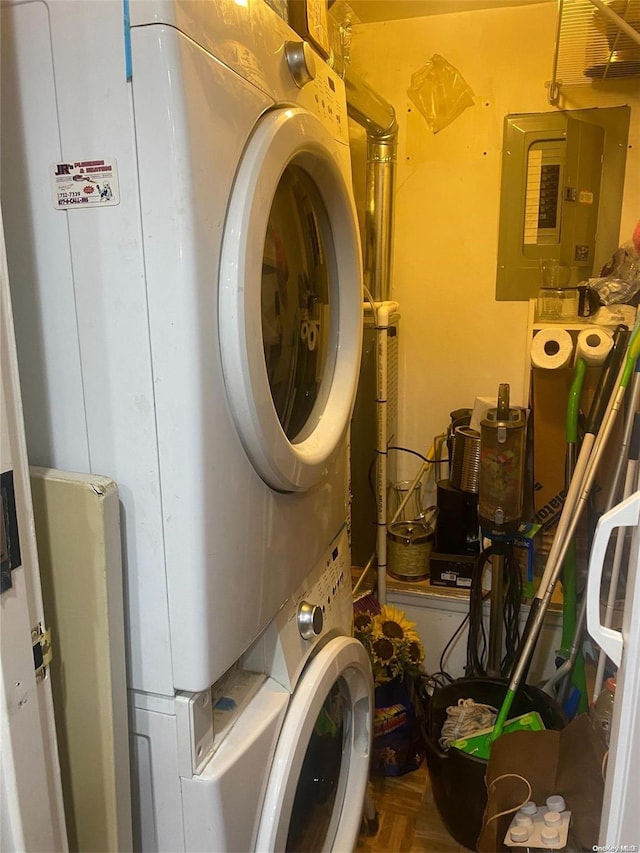 laundry area featuring electric panel, stacked washer and clothes dryer, and parquet flooring