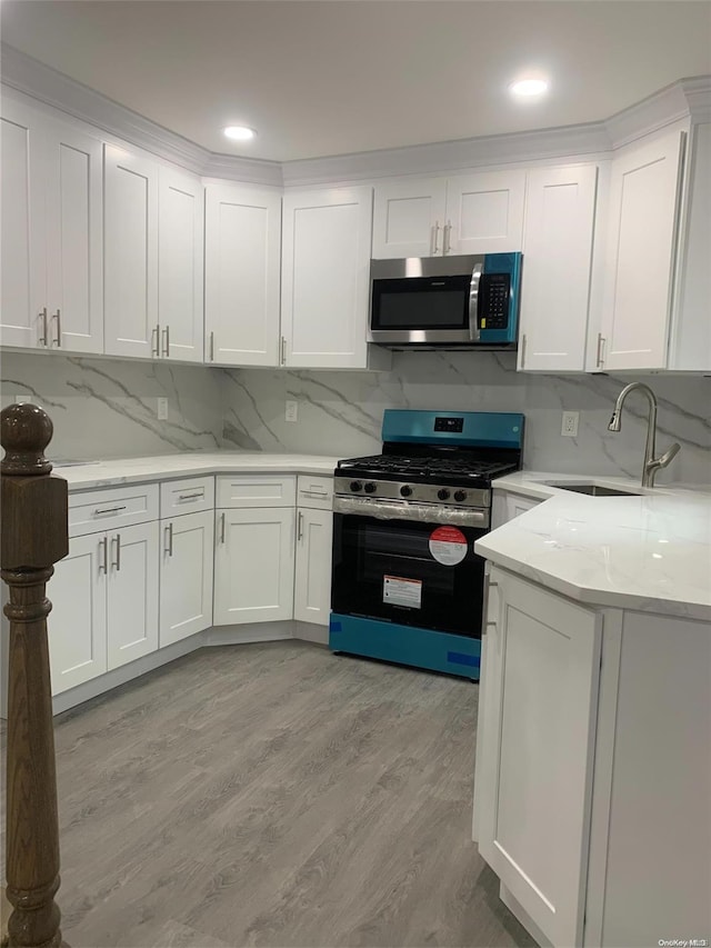 kitchen featuring white cabinets, appliances with stainless steel finishes, light hardwood / wood-style flooring, and sink