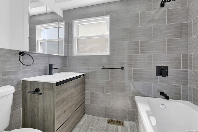 bathroom featuring vanity, tile walls, and toilet