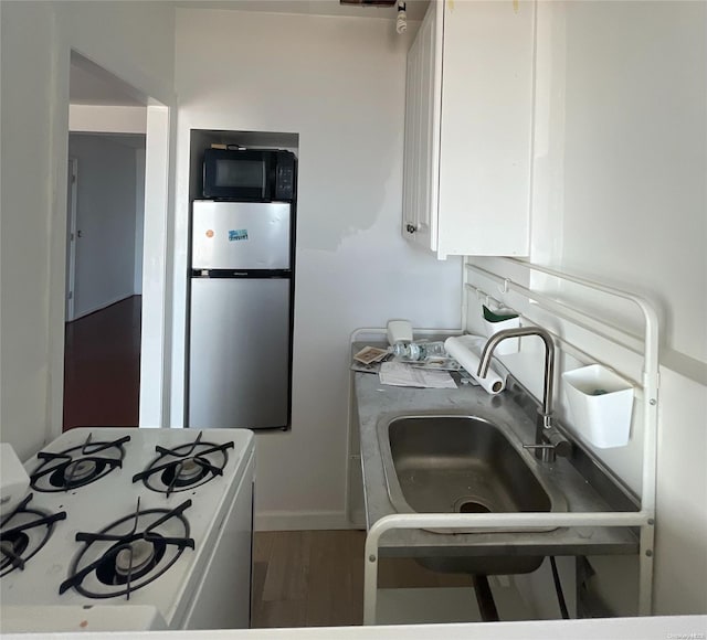 kitchen with stainless steel refrigerator, sink, white range with gas stovetop, and hardwood / wood-style flooring