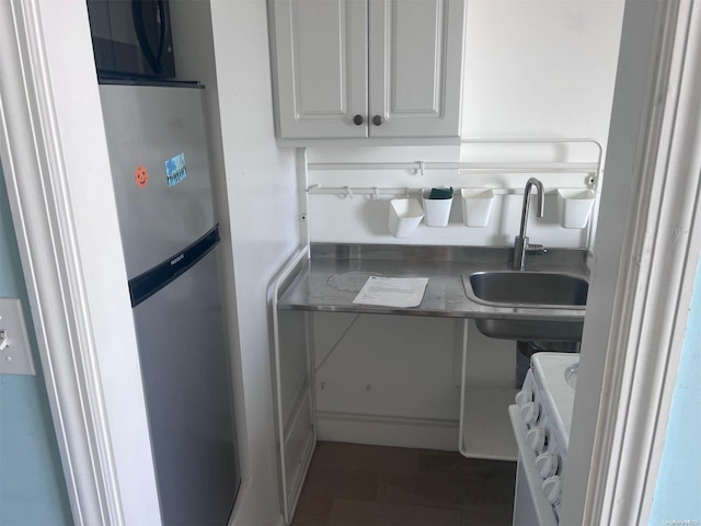 kitchen with white cabinets, white range oven, dark wood-type flooring, and sink