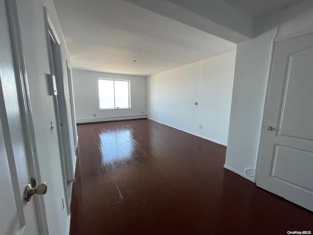 empty room featuring dark hardwood / wood-style flooring and baseboard heating