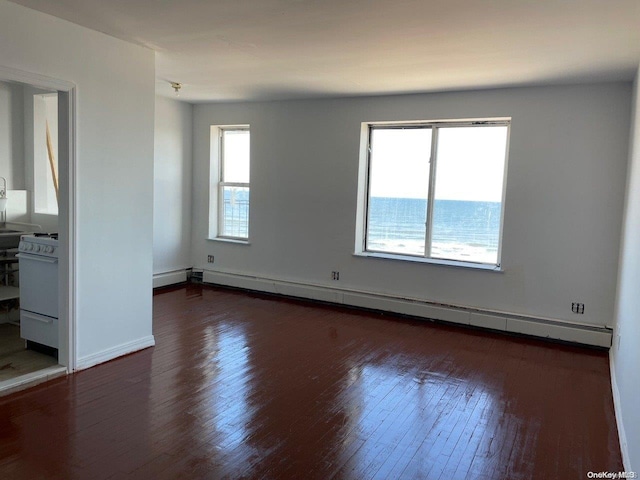 empty room with plenty of natural light, dark hardwood / wood-style floors, and a baseboard heating unit