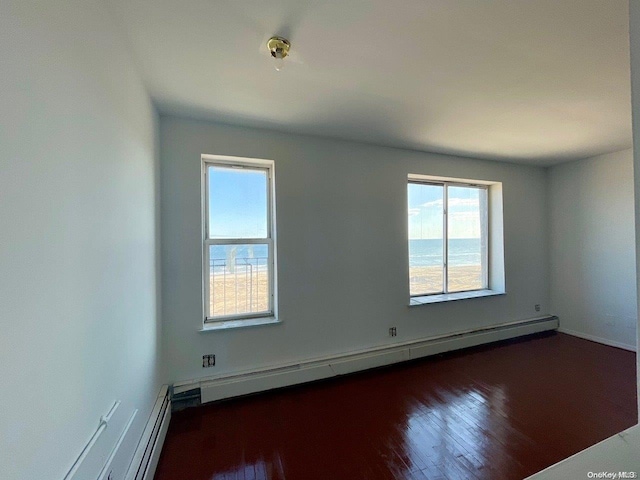 empty room with a baseboard radiator, dark wood-type flooring, and a water view