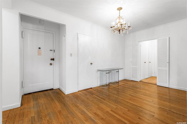 interior space featuring wood-type flooring, ornamental molding, and a notable chandelier