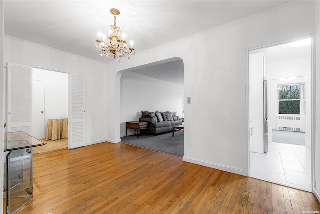 interior space with hardwood / wood-style floors, crown molding, radiator, and a chandelier