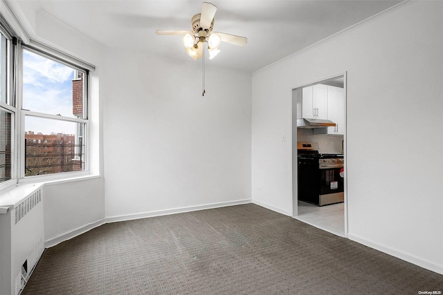 carpeted spare room featuring ceiling fan, radiator heating unit, and crown molding