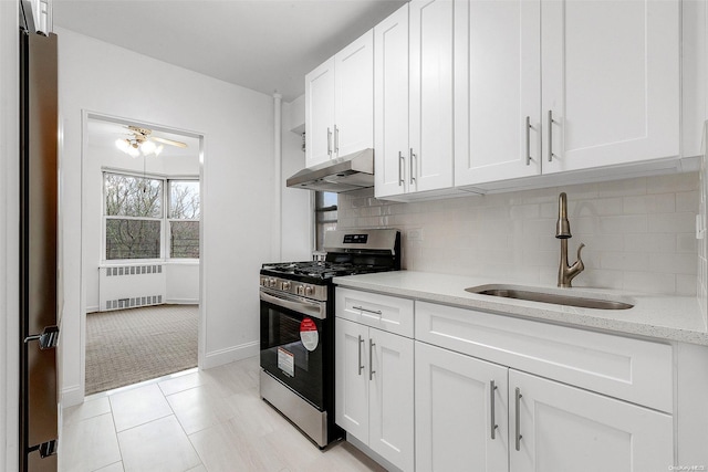 kitchen featuring radiator heating unit, sink, white cabinetry, and stainless steel gas range