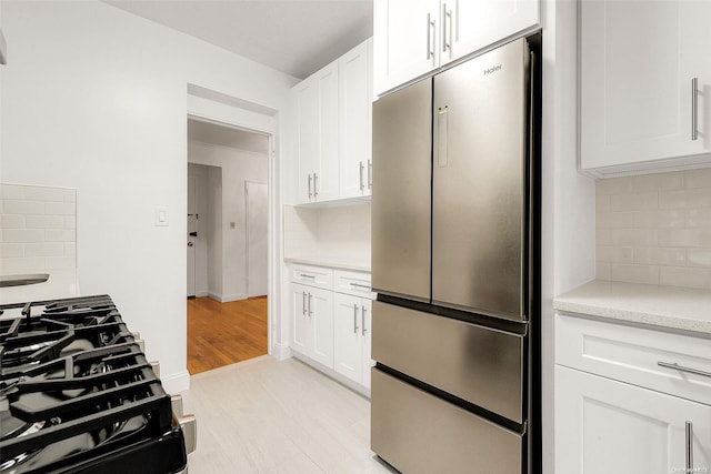 kitchen featuring white cabinetry, backsplash, high quality fridge, and light hardwood / wood-style flooring