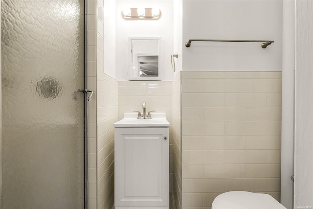 bathroom with walk in shower, vanity, toilet, and tile walls