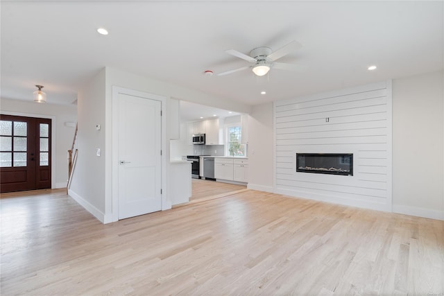 unfurnished living room with light hardwood / wood-style floors, ceiling fan, and a fireplace