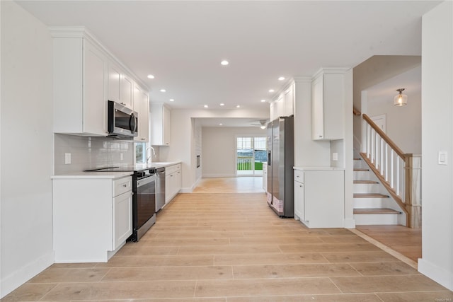 kitchen featuring backsplash, light hardwood / wood-style floors, sink, white cabinetry, and stainless steel appliances