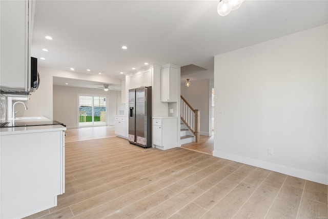 kitchen featuring ceiling fan, sink, light hardwood / wood-style flooring, stainless steel fridge with ice dispenser, and white cabinets