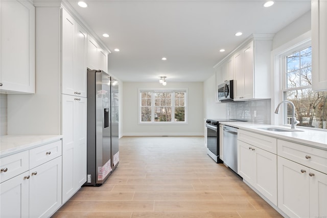 kitchen with plenty of natural light, sink, white cabinetry, and stainless steel appliances