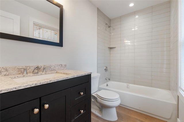 full bathroom with toilet, tiled shower / bath, vanity, and hardwood / wood-style flooring