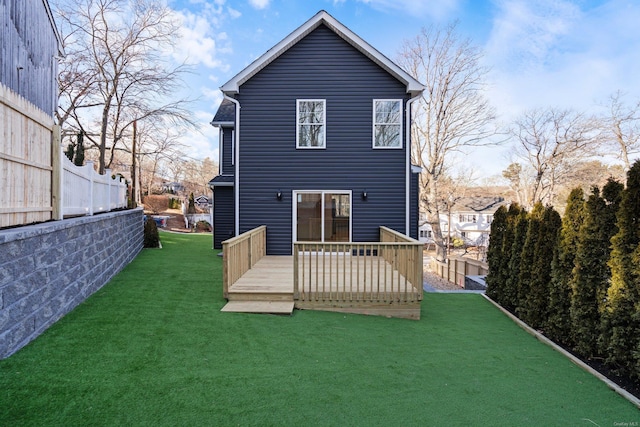 rear view of house featuring a wooden deck and a yard