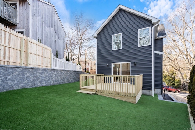 rear view of house with a lawn and a wooden deck