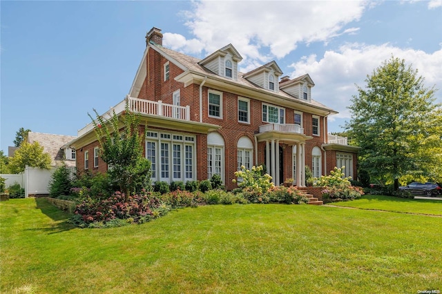 colonial-style house featuring a front yard and a balcony