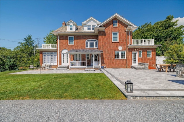 view of front of home with a patio area, a balcony, and a front lawn