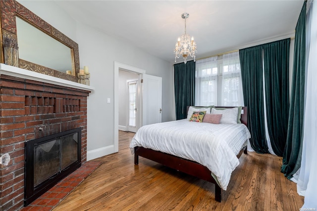 bedroom featuring a fireplace, hardwood / wood-style floors, and a chandelier