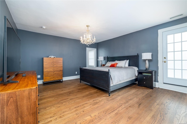 bedroom featuring light hardwood / wood-style floors, multiple windows, and a notable chandelier