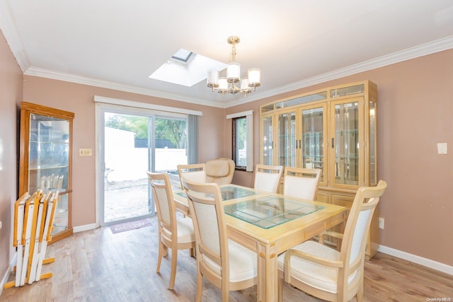 dining area with crown molding, a notable chandelier, light wood-type flooring, and a skylight