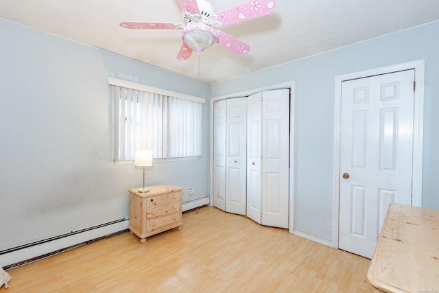 bedroom with baseboard heating, ceiling fan, and wood-type flooring