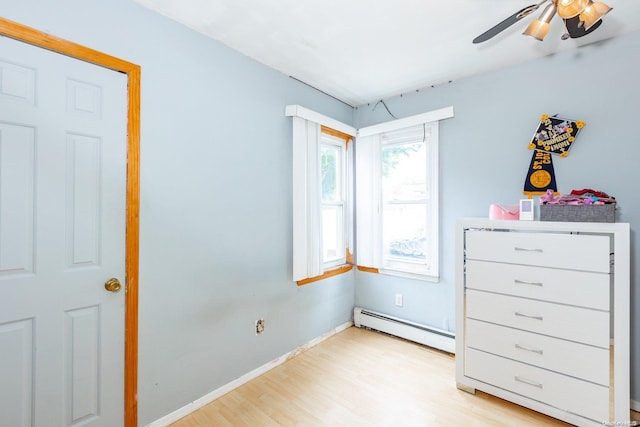 unfurnished bedroom featuring a baseboard radiator, ceiling fan, and light wood-type flooring