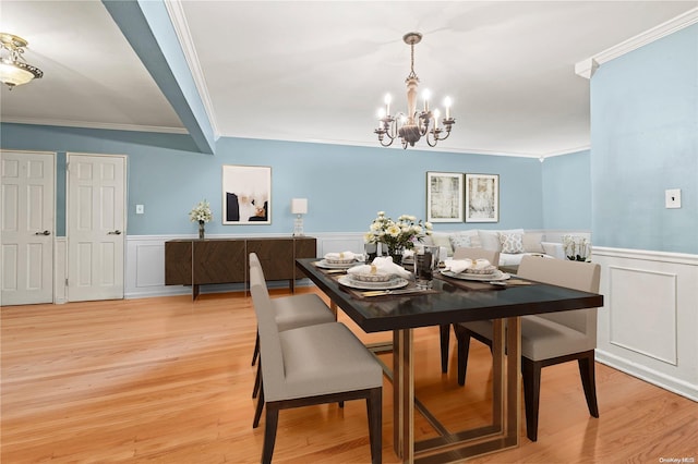 dining area with a notable chandelier, light hardwood / wood-style floors, and crown molding