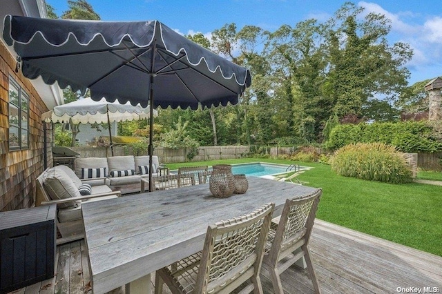 wooden deck with an outdoor living space, a fenced in pool, and a lawn