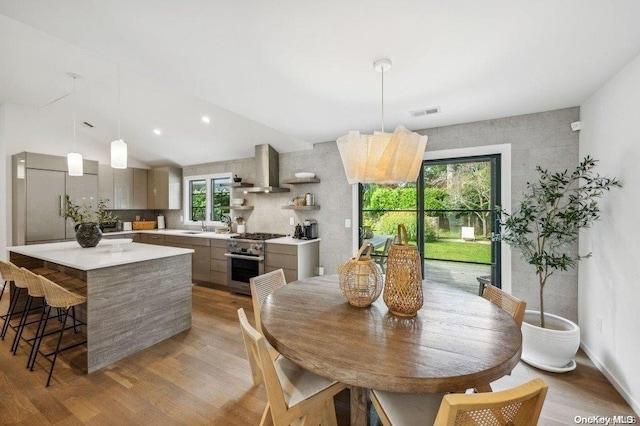 dining space featuring sink, a chandelier, lofted ceiling, and light wood-type flooring