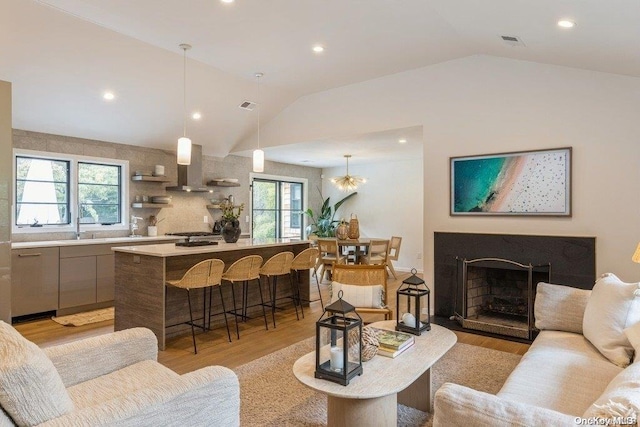 living room featuring a wealth of natural light, light hardwood / wood-style flooring, and vaulted ceiling