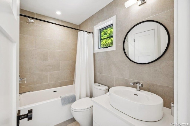 full bathroom featuring vanity, shower / bathtub combination with curtain, tile walls, and toilet