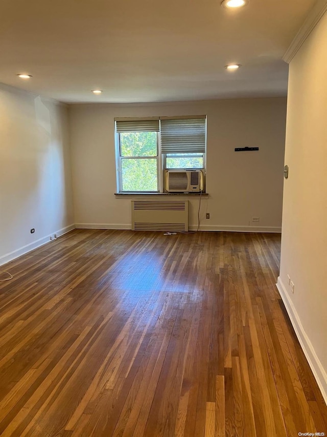 spare room featuring dark wood finished floors, baseboards, radiator, and recessed lighting