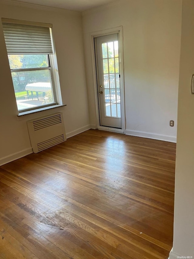 unfurnished room with baseboards, radiator heating unit, and wood finished floors