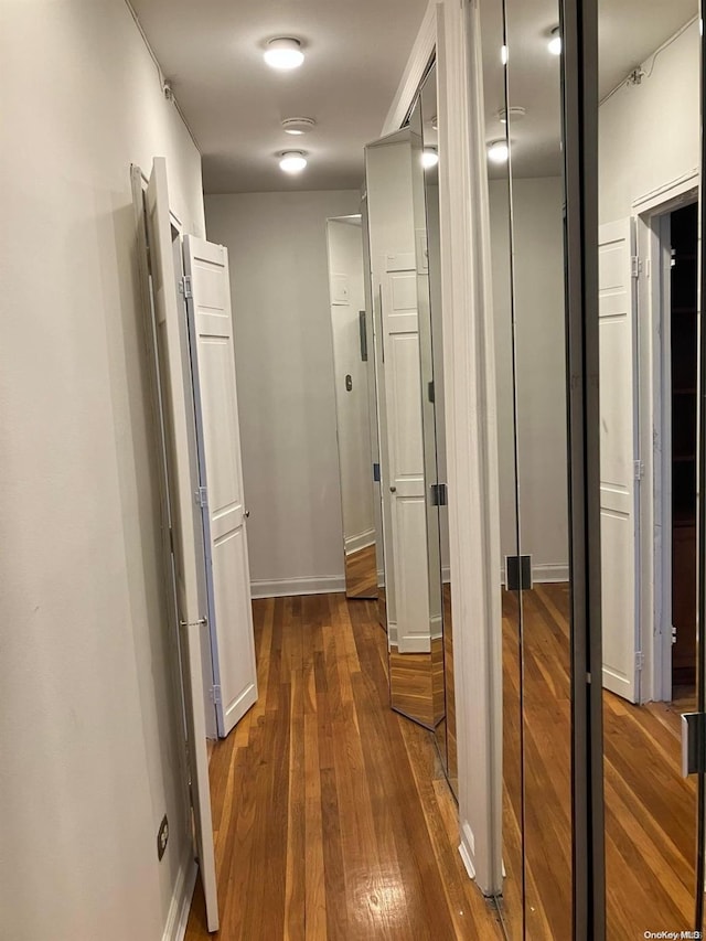 hallway featuring baseboards and dark wood-style flooring