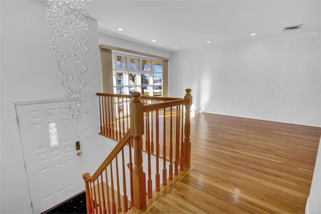 stairway featuring wood finished floors, visible vents, an inviting chandelier, recessed lighting, and a decorative wall