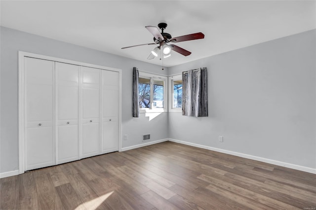 unfurnished bedroom with visible vents, baseboards, a closet, and wood finished floors