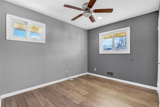 unfurnished room featuring ceiling fan, visible vents, baseboards, and wood finished floors