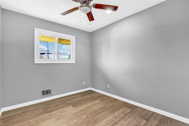 unfurnished room featuring visible vents, a ceiling fan, baseboards, and wood finished floors