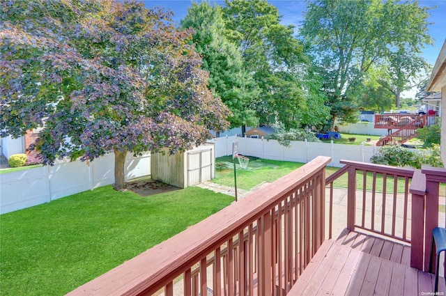 deck featuring a storage unit, a lawn, an outdoor structure, and a fenced backyard