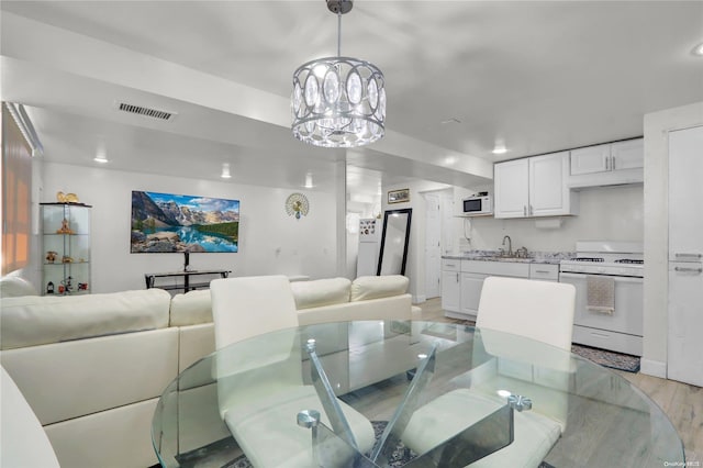 dining room with light wood finished floors, a notable chandelier, and visible vents