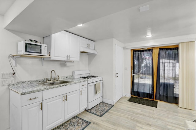 kitchen featuring white appliances, white cabinetry, light wood-style floors, and a sink