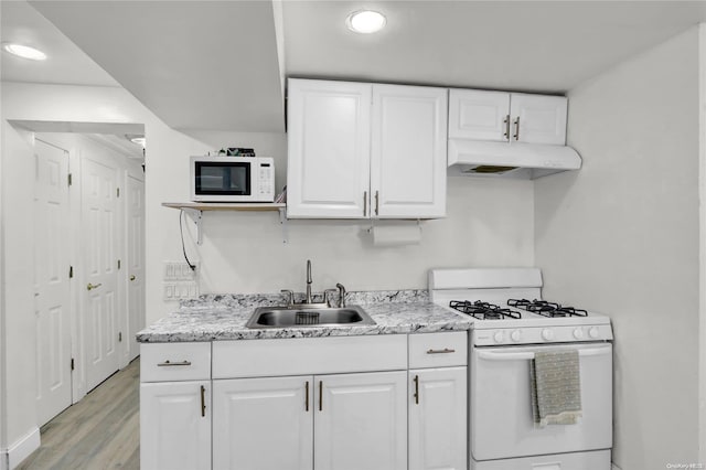 kitchen with under cabinet range hood, light wood-type flooring, white appliances, white cabinetry, and a sink