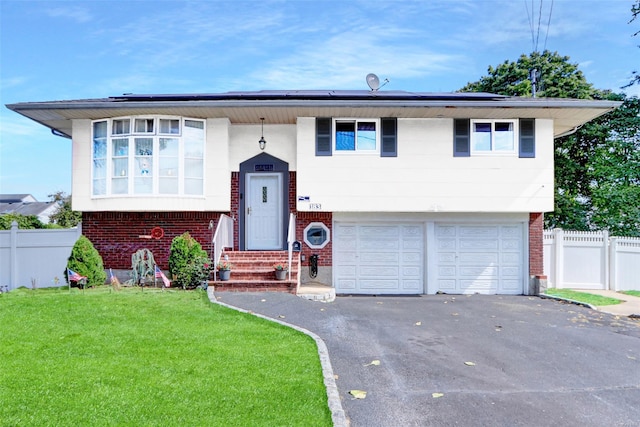 bi-level home with brick siding, solar panels, driveway, and fence