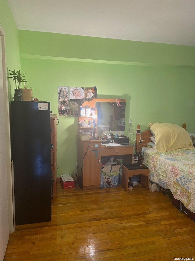 bedroom with black refrigerator and hardwood / wood-style floors