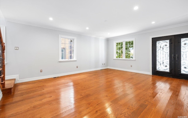 entrance foyer with french doors, light wood-type flooring, plenty of natural light, and crown molding