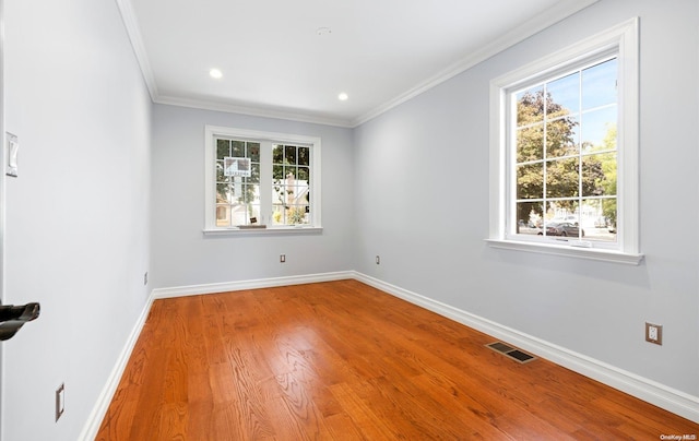 spare room with wood-type flooring, plenty of natural light, and crown molding