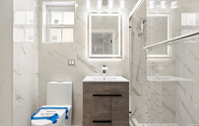 bathroom with vanity, a shower with shower door, tile walls, and toilet