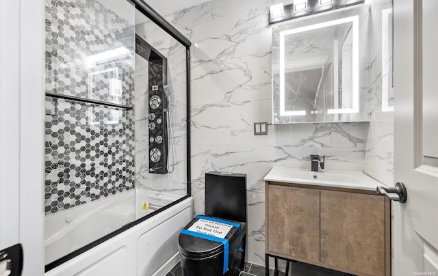 bathroom featuring vanity, bath / shower combo with glass door, and tile walls